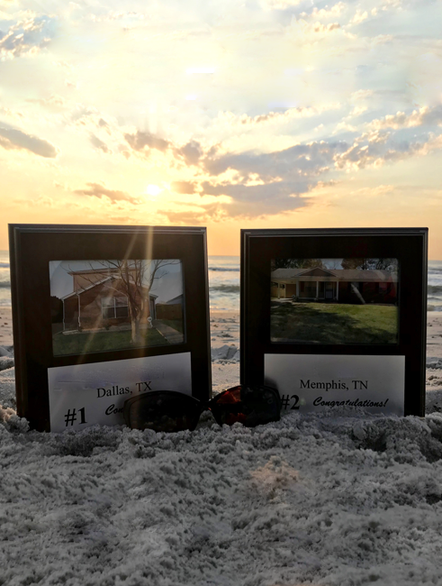 Two REI property plaques in sand on the beach at sunset